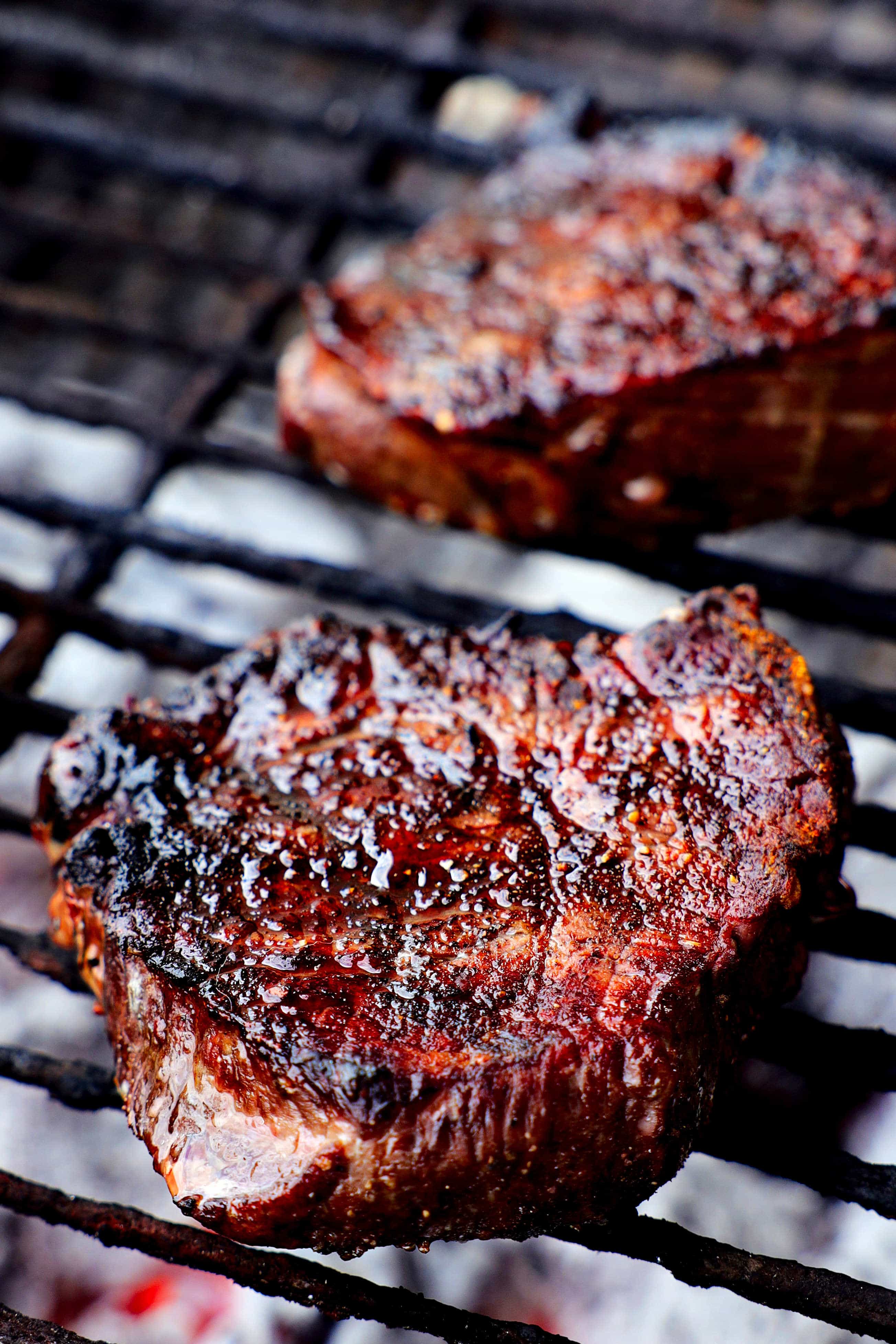 two steaks on a charcoal grill