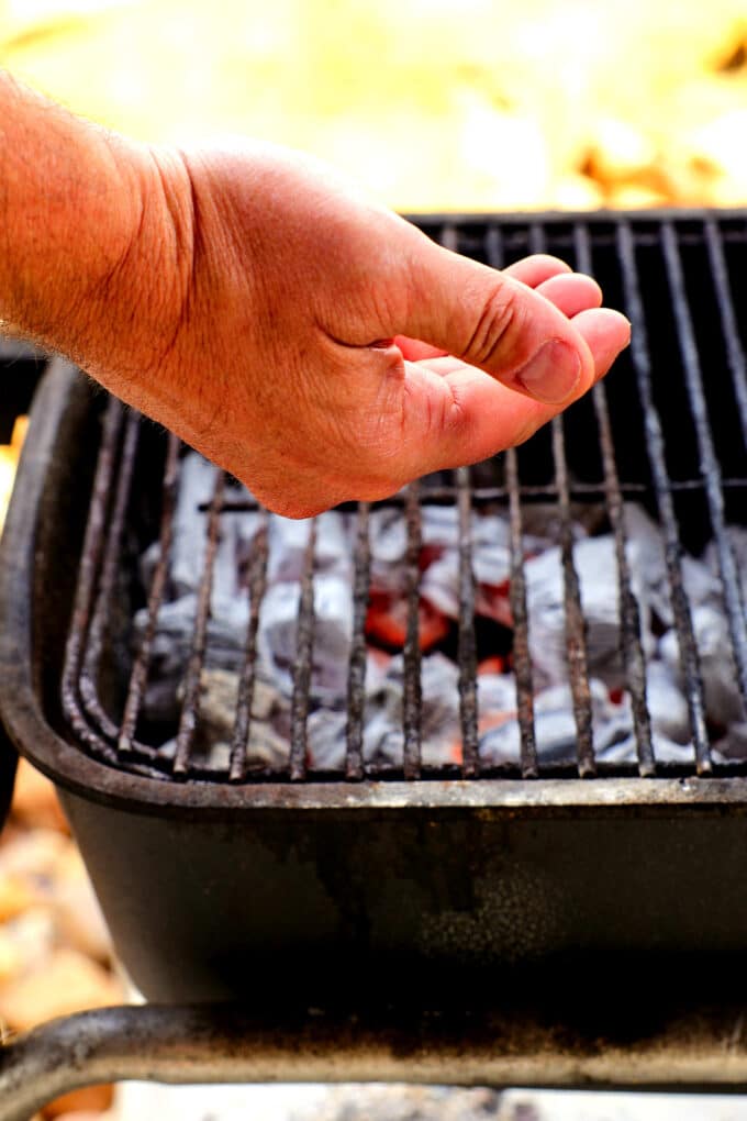 a hand checking the temperature of a grill