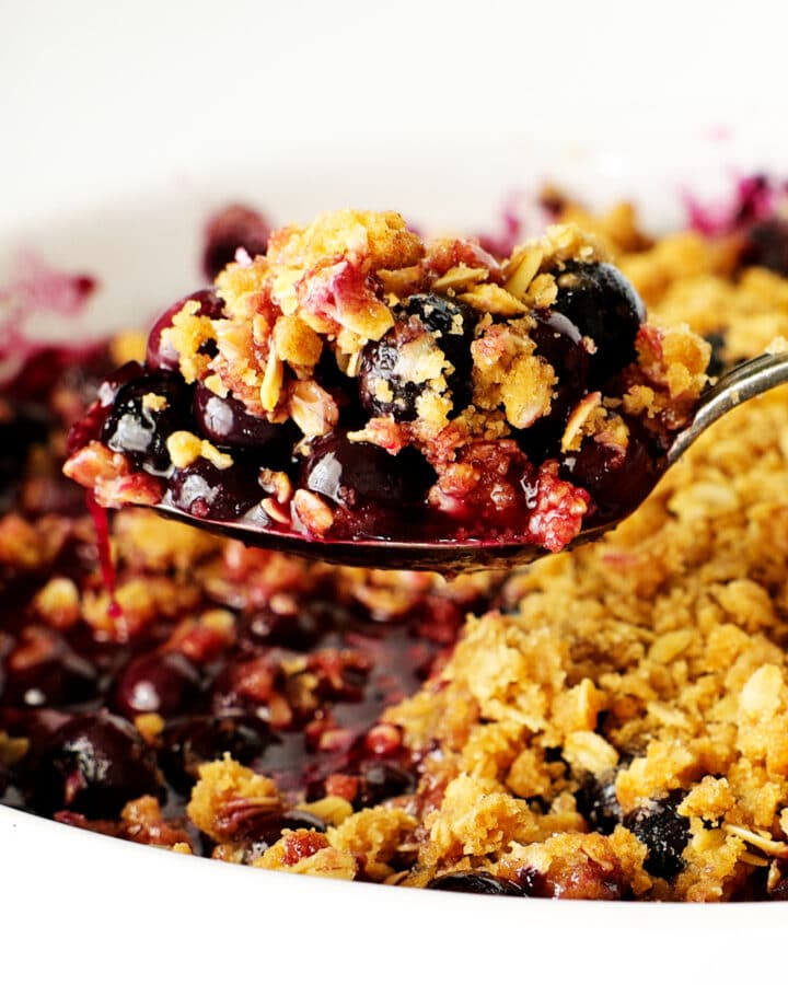 A spoonful of blueberry crisp scooped from the pan