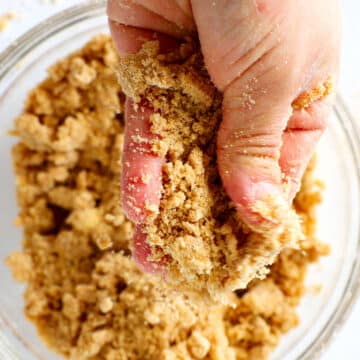 A hand squishing butter into the crumble mixture
