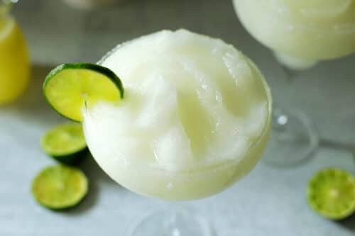 an overhead view of A frozen margarita in a margarita glass with a lime wheel on the side