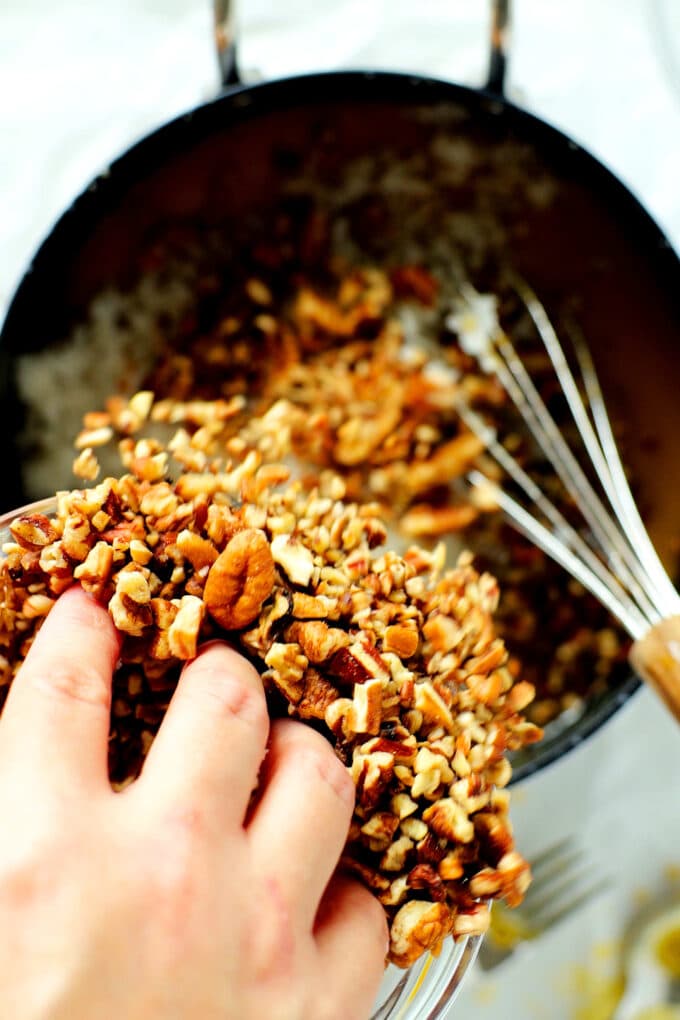 chopped pecans being added to a saucepan
