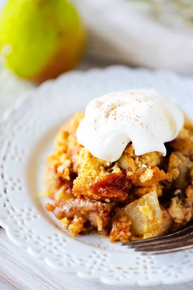 pear cobbler on a plate with a dollop of whipped cream on top