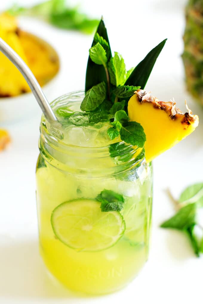 A pineapple mojito in a mason jar with pineapple and mint garnish