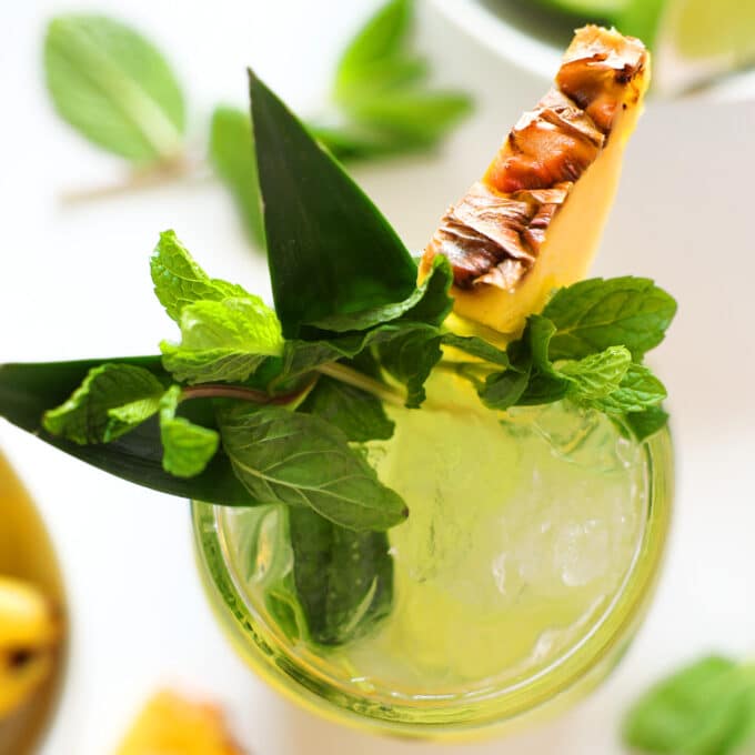 And overhead view of a pineapple Mojito with a pineapple leaf, mint, and a slice of pineapple as garnish