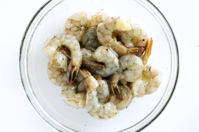 raw shrimp in a glass bowl with oil and seasoning