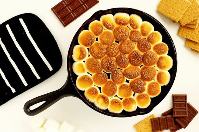 An overhead view of toasty smores dip with graham crackers and chocolate beside it