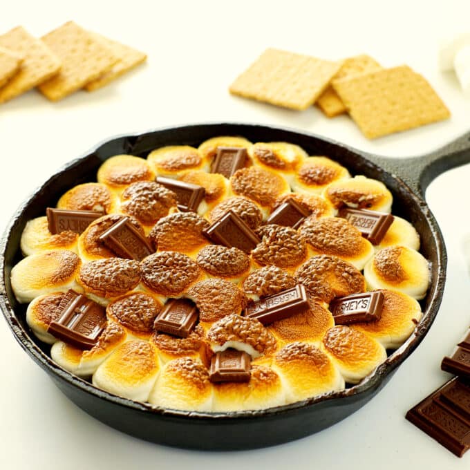 smores dip in a cast iron pan with Hershey chocolate pieces pressed into the top