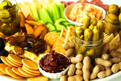A side view of a southern appetizer board showing okra, peanuts, crackers, cheeses, fruit, and veggies