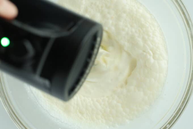 an overhead view of whipping cream being whipped with a handheld mixer