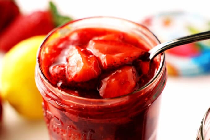 Strawberry Compote in a jar with a spoon. big slices of berries with jammy coating