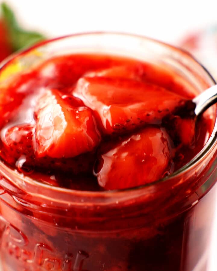 Strawberry Compote in a jar with a spoon. big slices of berries with jammy coating