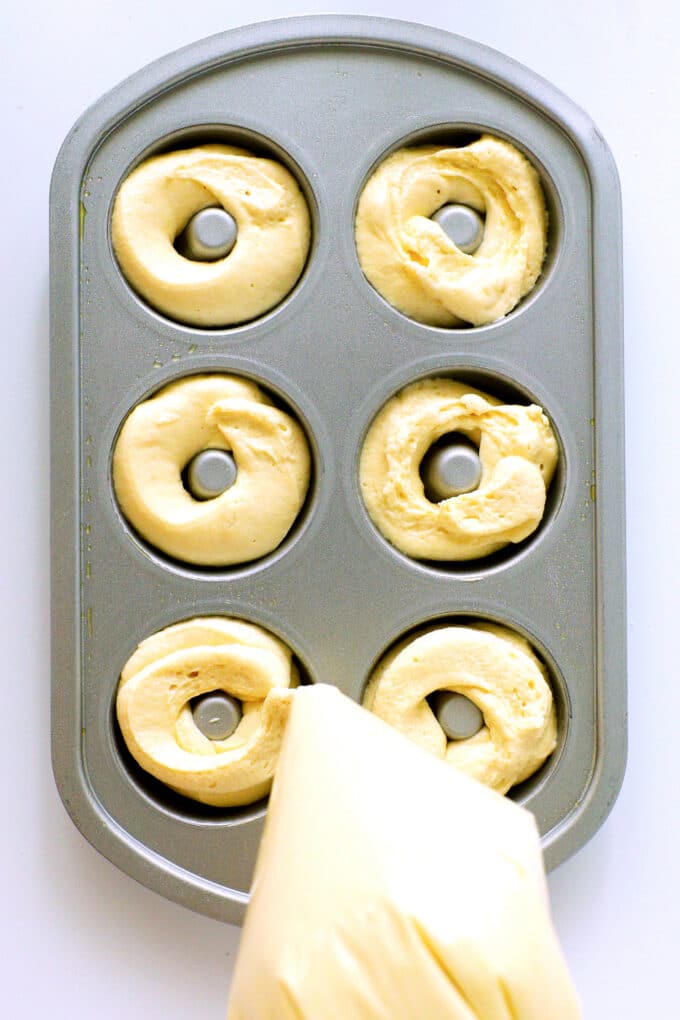 a large zip top bag being used to pipe dough into a donut pan