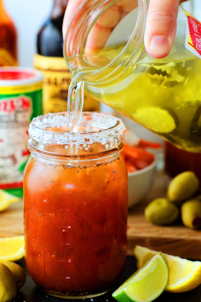 pickle juice being poured from the jar into the Bloody Mary 