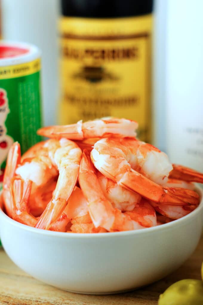 a close up of a bowl of cooked shrimp with the tails still on