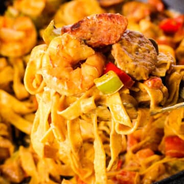 a big scoop of jambalaya pasta on a fork with sausage, peppers, shrimp and noodles