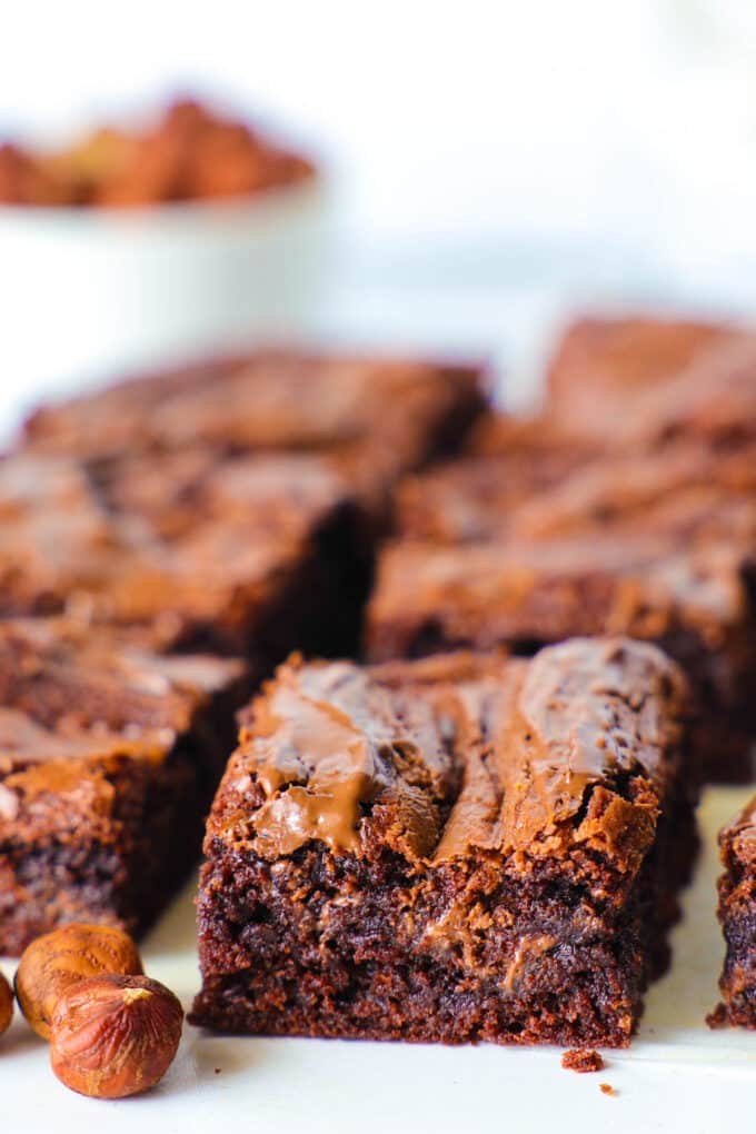 the brownie slices sitting on a counter, evenly spaced out with some hazelnuts sitting beside them