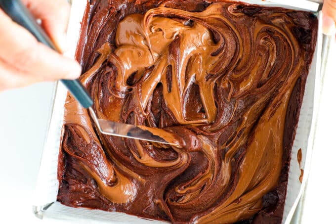 a frosting knife being used to swirl the Nutella mixture into the brownie batter