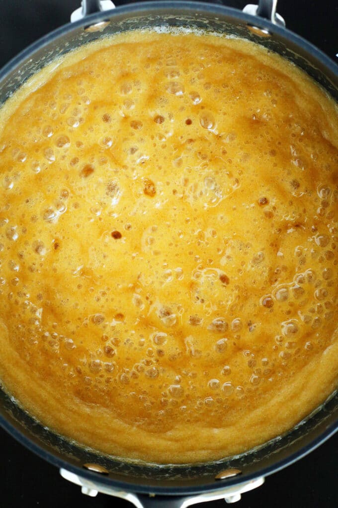 An overhead shot of the praline mixture bubbling in a pan, it is golden in color