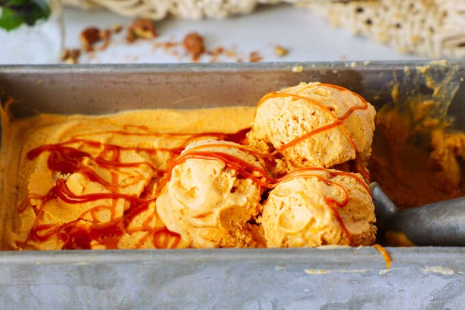 Three scoops of pumpkin ice cream sit on top of what's left in the pan. The whole thing is drizzled with caramel sauce