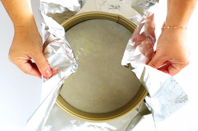 Hands wrapping a spring form pan in foil