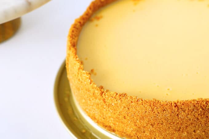 a close up of the cheesecake fresh out of the oven and with the sides of the pan removed. the top is smooth and cream colored