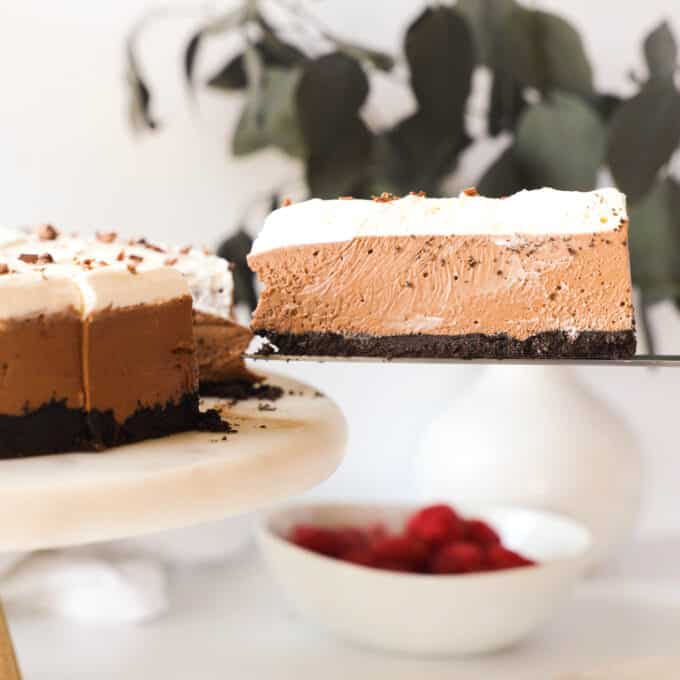 A slice of chocolate mousse pie being lifted off the cake plate with the rest of the pie on it