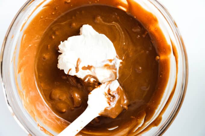 Whipped cream being folded into the chocolate mixture with a rubber spatula
