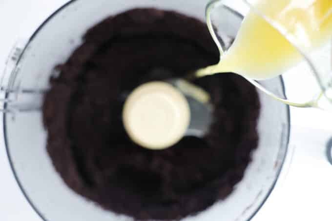 Butter being streamed into a food processor of Oreo crumbs