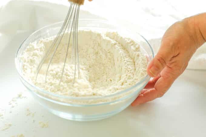 Dry ingredients being mixed with a whisk in a glass bowl