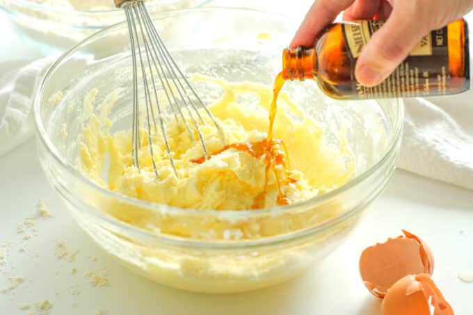 Vanilla extract being poured from the bottle into the creamed butter mixture
