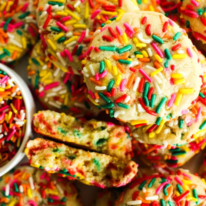 An overhead look at a pile of Funfetti Cookies. one broken in half to show the sprinkles on the inside