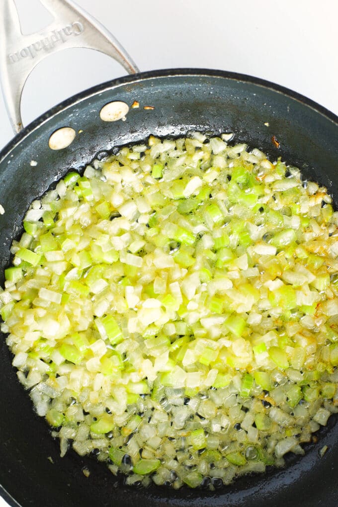 diced onion and celery cooking in a pan with butter