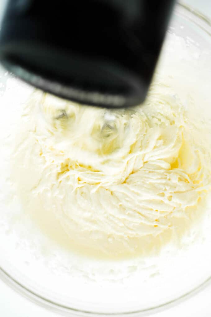 A hand mixer being used to cream sugar and egg.