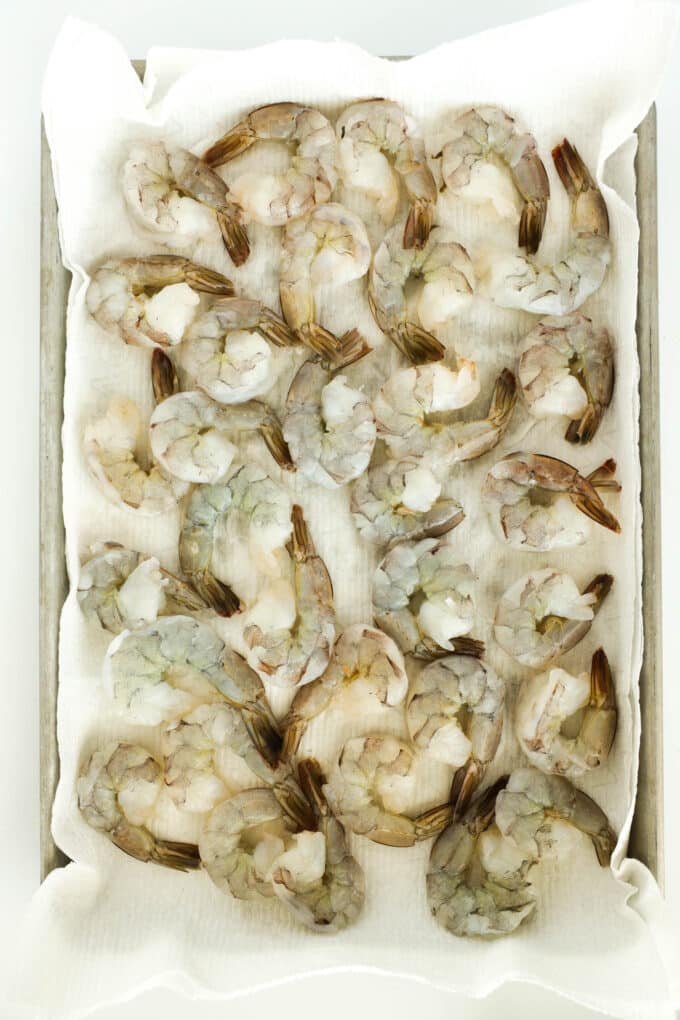 Raw, jumbo shrimp laying in a single layer on paper towels.