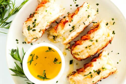 An overhead shot of a plate of Baked Lobster Tails with a ramekin of melted butter on the side.