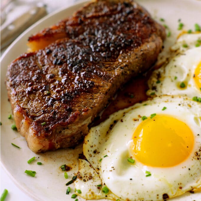 A close up of a plate of Steak and Eggs. The steak and tender and juicy and the eggs are sunny side up.