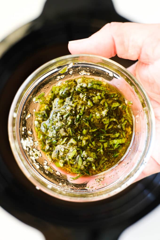 A small bowl of the herb and oil mixture being held up to the camera.