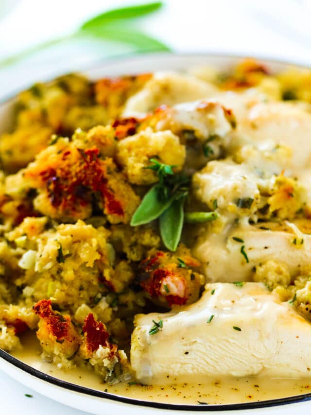 A plate of Crockpot Chicken and Stuffing with gravy and a sage leaf garnish.