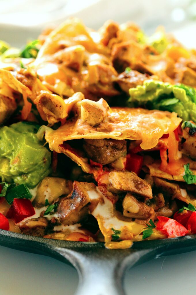 A view from the side of a skillet of Chicken Nachos, showing the layers of ingredients.