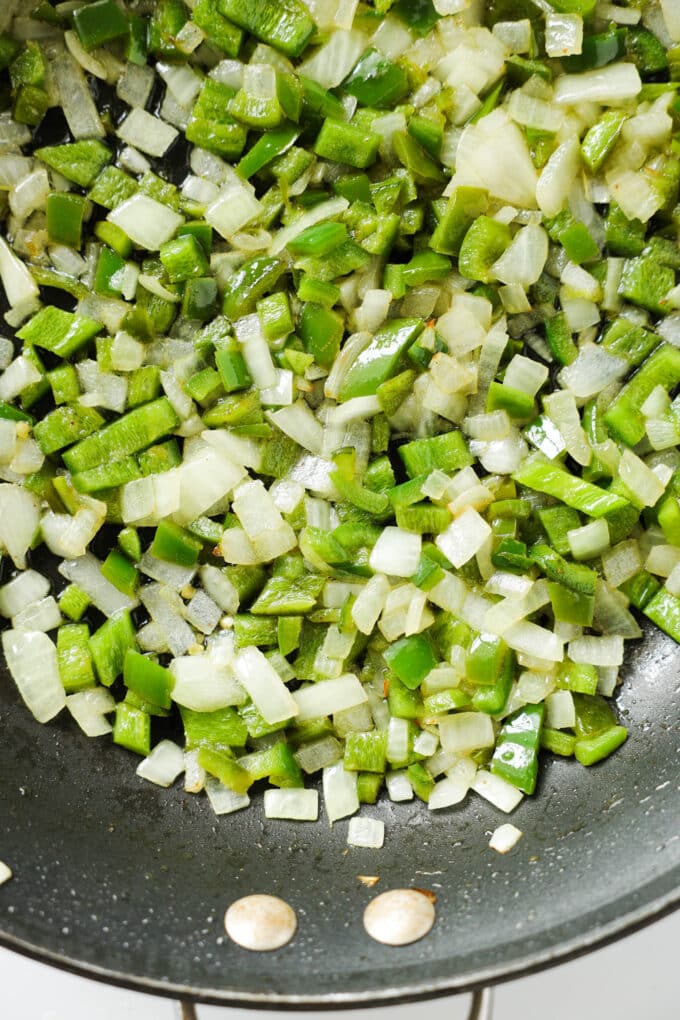Diced onion and jalapeños being sautéed in a skillet.