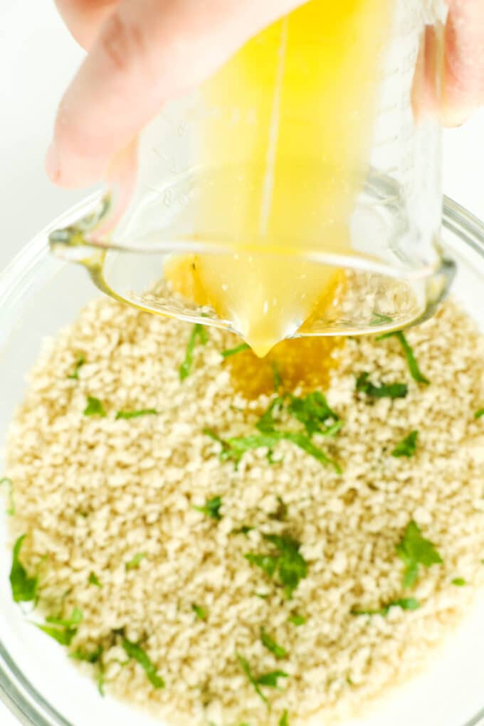 Melted butter being poured into the breadcrumb mixture.
