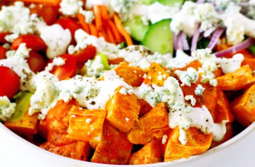 A close up of Buffalo Chicken Salad. The chicken in buffalo sauce is in the foreground, with the vegatables behind it.