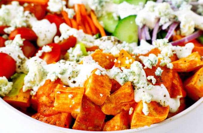 A close up of Buffalo Chicken Salad. The chicken in buffalo sauce is in the foreground, with the vegatables behind it. 