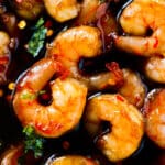 A close up of Honey Garlic Shrimp. The sauce is a thick glaze over the shrimp and they are sitting in plenty of extra sauce.