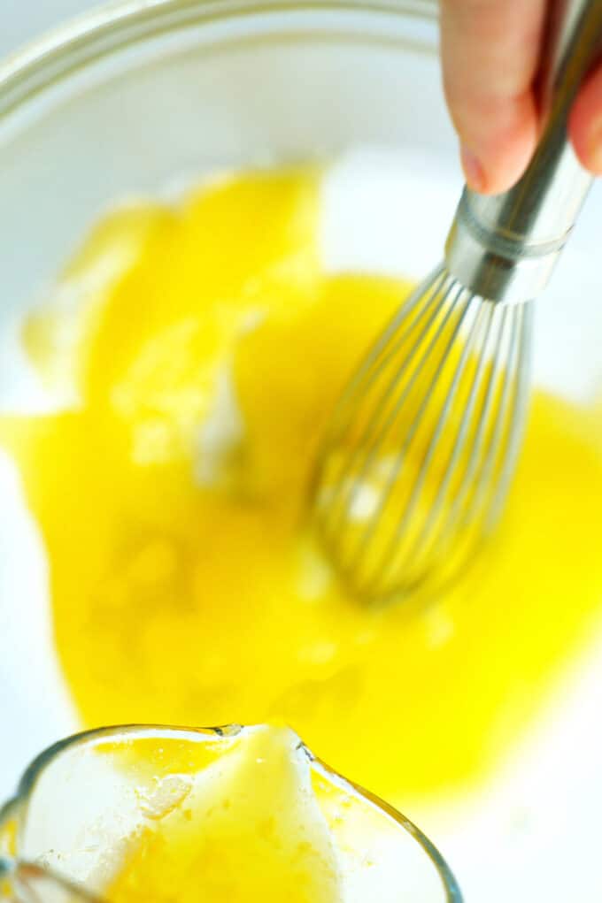 The melted butter being streamed into the bowl of eggs and sugar.