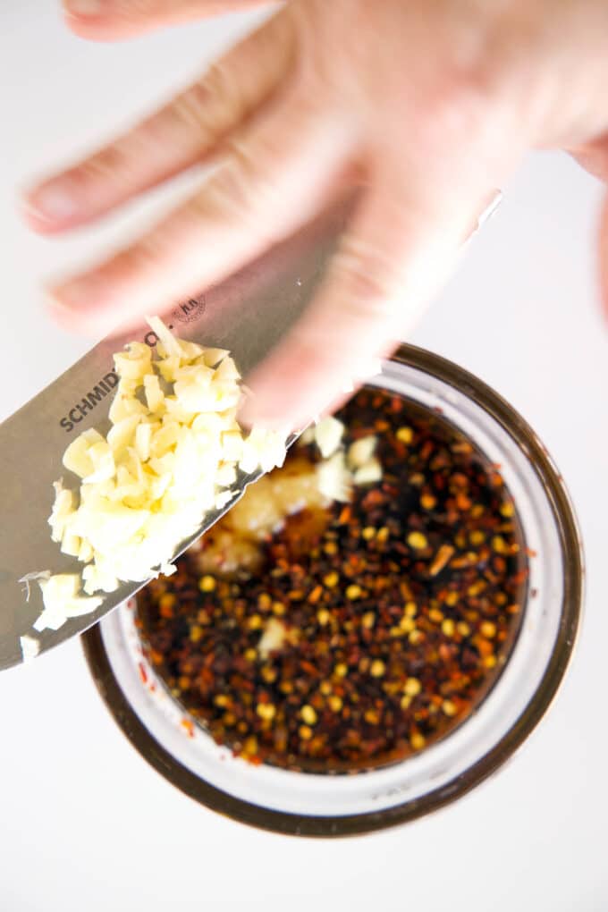 Minced garlic being added to the other sauce ingredients in a small bowl.