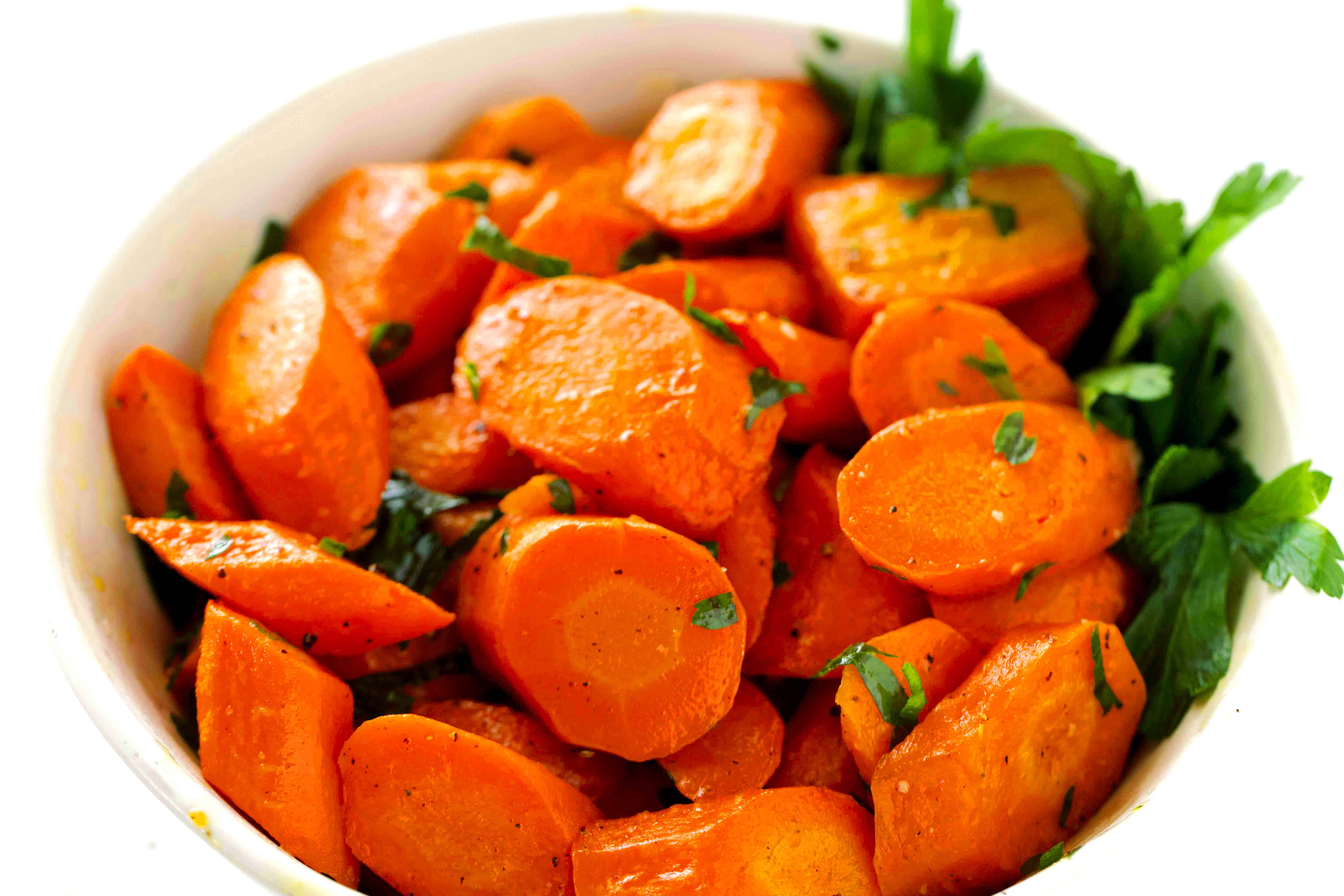 A profile view of Roasted Carrots in a bowl, with a parsley garnish.