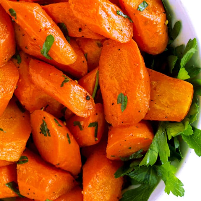 A close up, overhead view of Roasted Carrots in a bowl, with a parsley garnish.