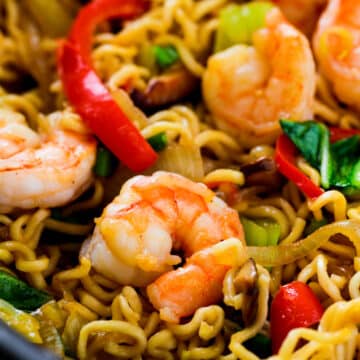 A close up of Shrimp Chow Mein. The noodles are somewhat yellow in color and vegetables are vibrant and bright.
